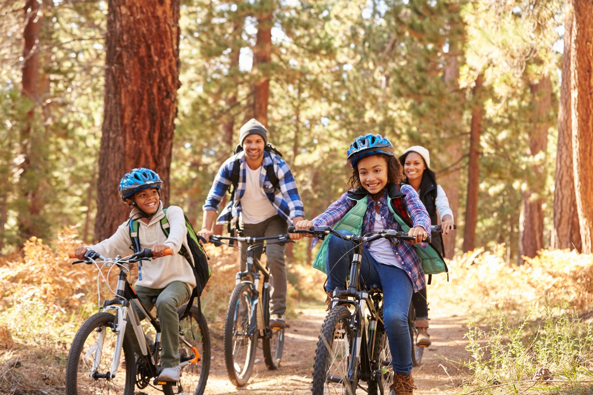 Afroamerikanische Familie Radfahren durch Herbst Wald