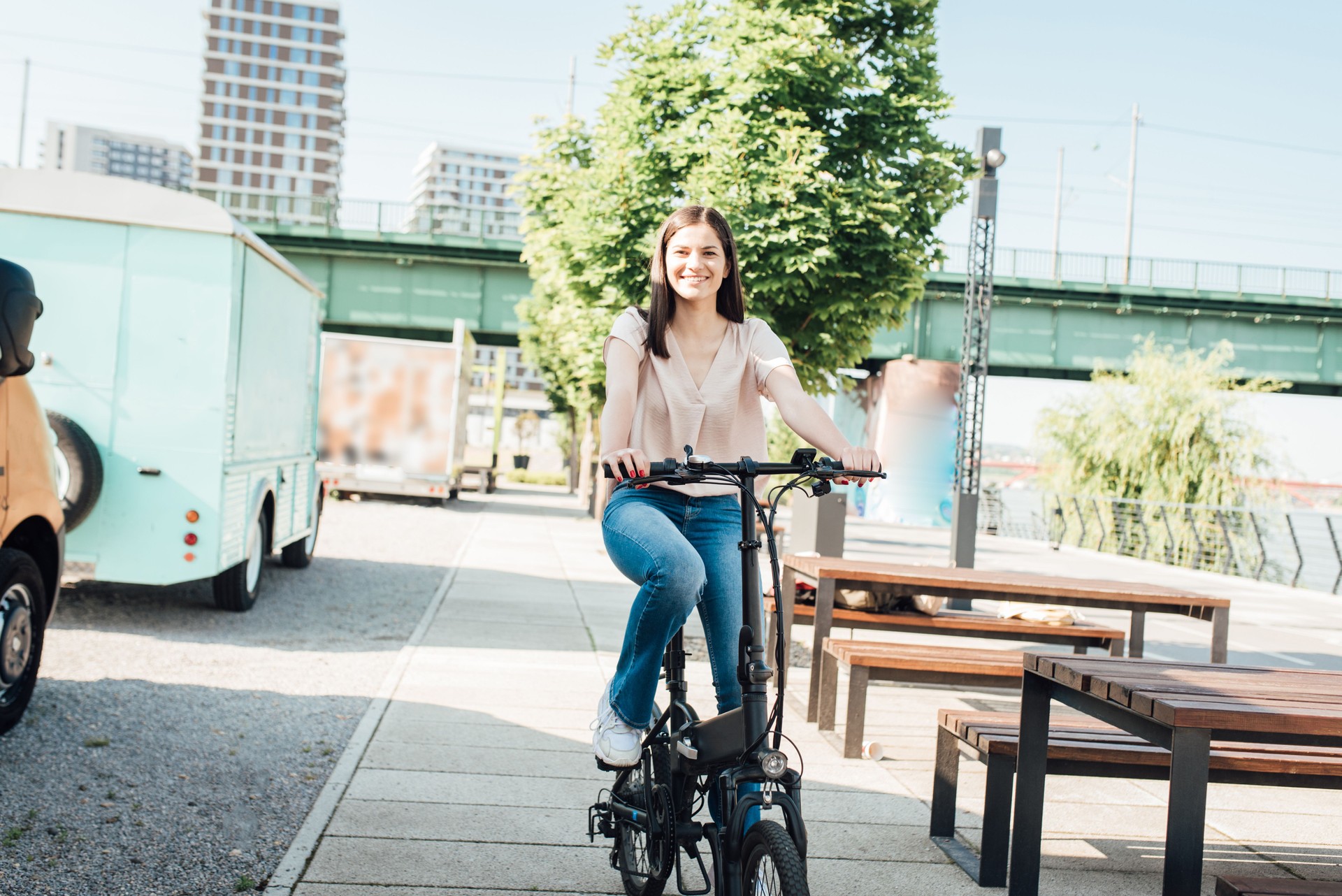 Schöne junge Frau, die auf dem Weg zur Arbeit mit dem Elektrofahrrad fährt